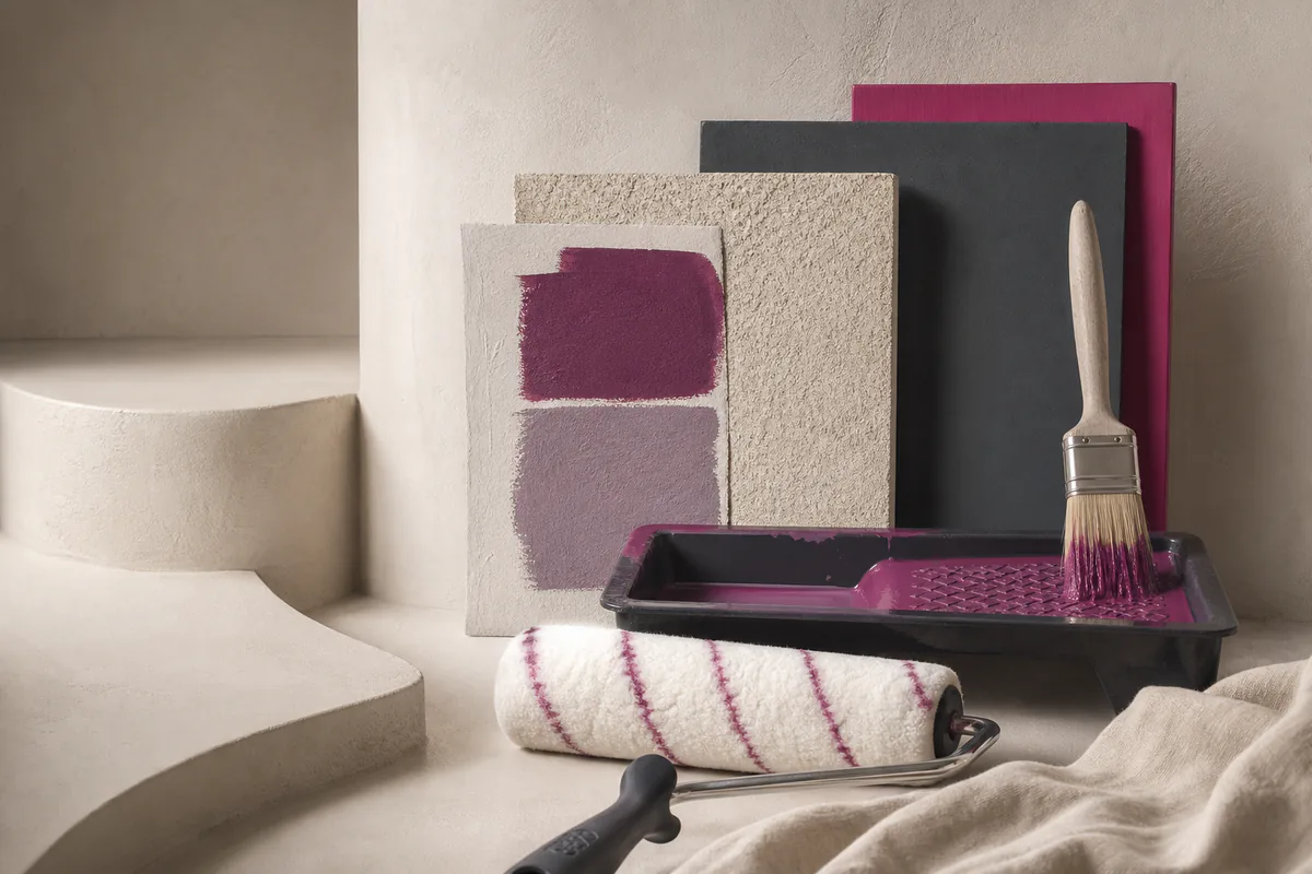 Painting tools, paint tray and textured sample surfaces in cream, magenta and violet